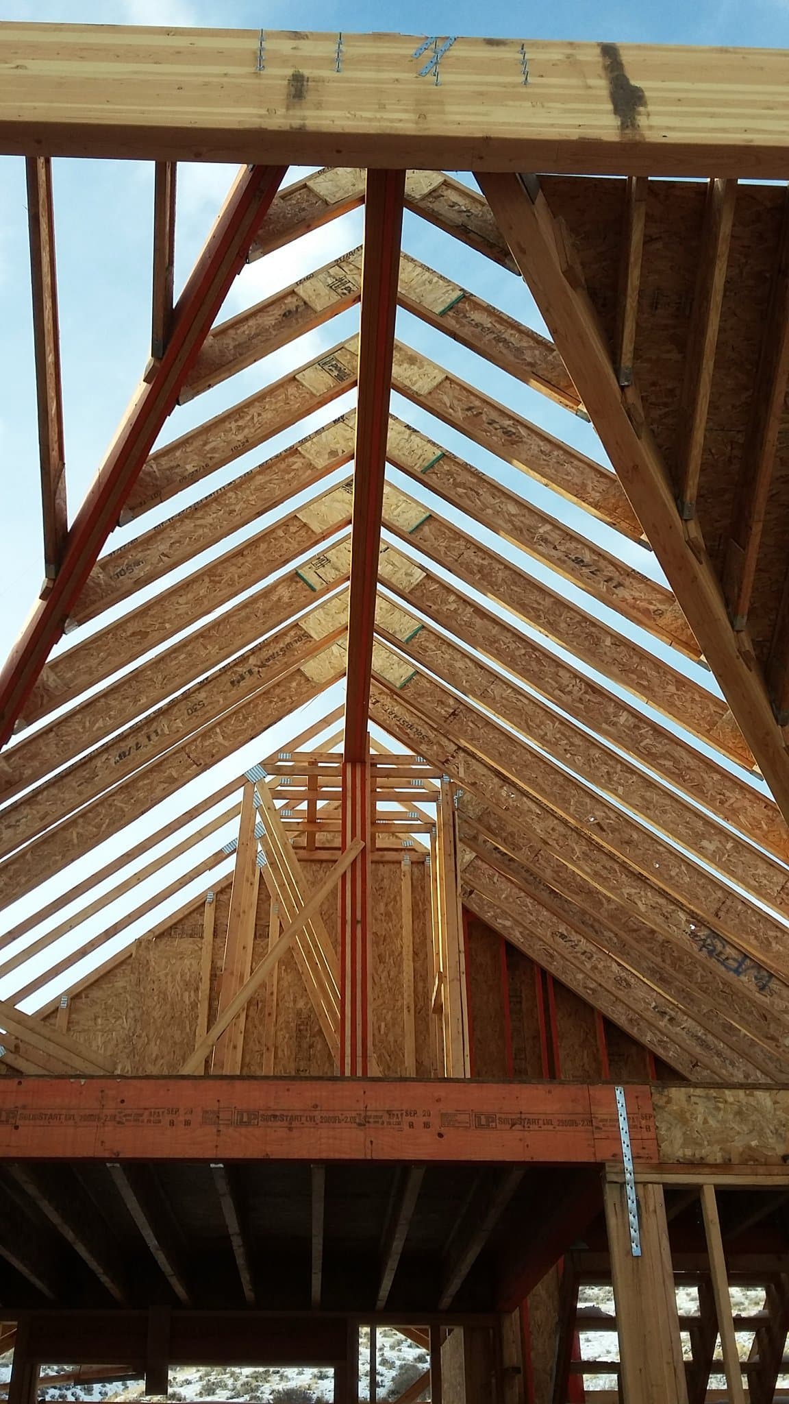 Custom home framing with roof trusses in progress by Elevation 100, Utah custom home builder